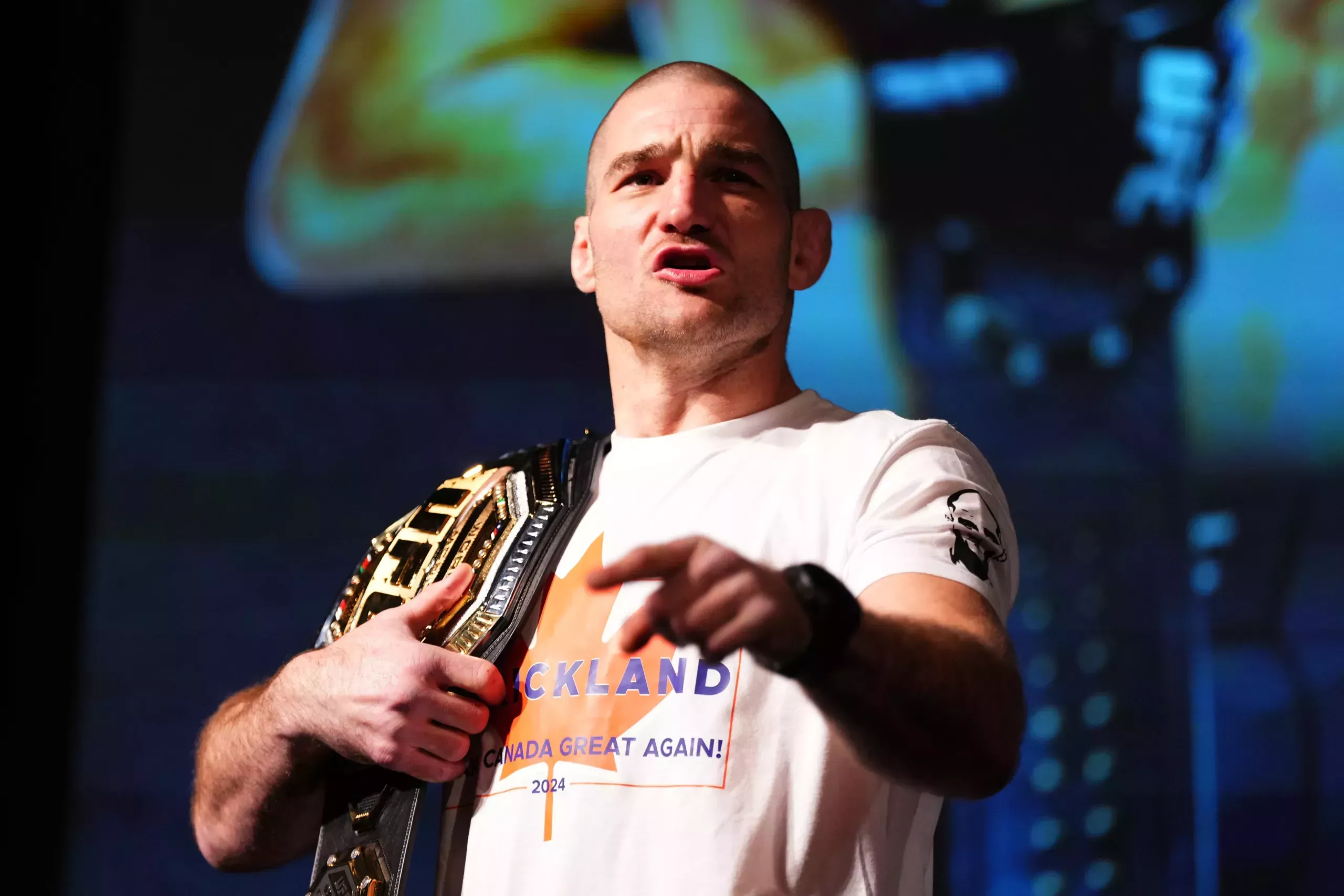 Sean Strickland in a white t-shirt with a championship belt.