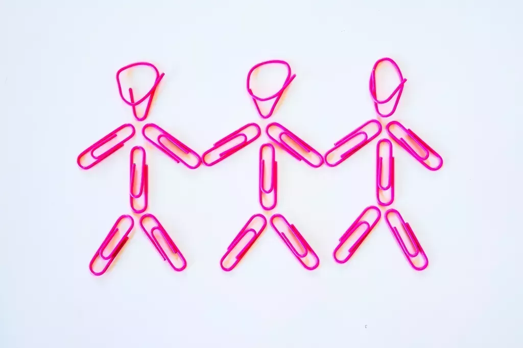 A conceptual idea of a polygamous lesbian relationship. Three women holding hands, with arms lowered. Represented by stereotypical pink colours for girls, it also represents happiness, alternative lifestyles and simplicity. Studio shot on a white background.