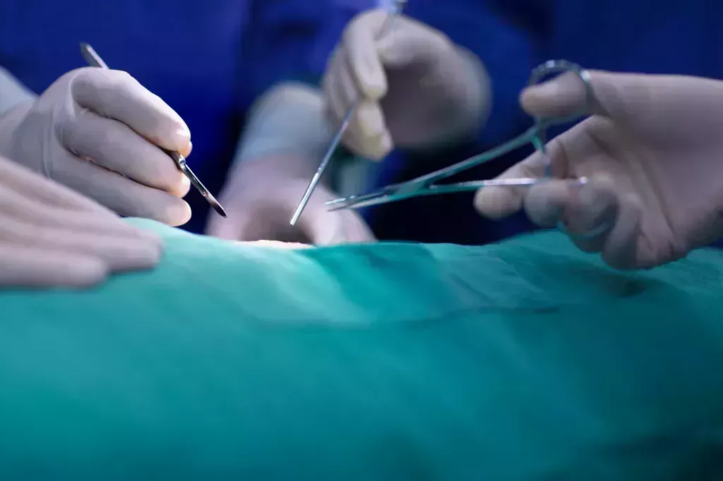 Surgeons holding a variety of tools during an operation.