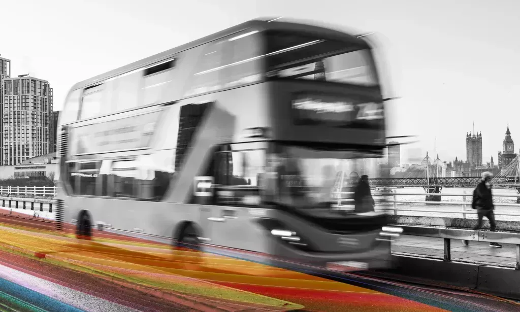 A black and white picture of a TfL bus in London with rainbow Pride colours superimposed across the road