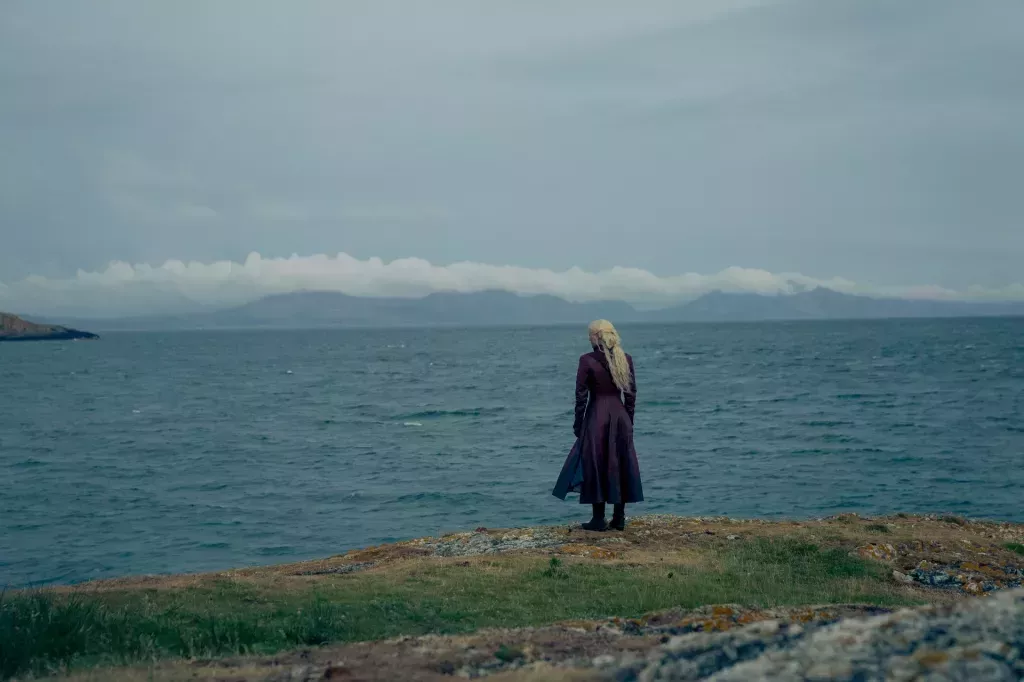 Emma D'Arcy as Queen Rhaenyra Targaryen in House of the Dragon season 2. Their character is looking out at the wide ocean.