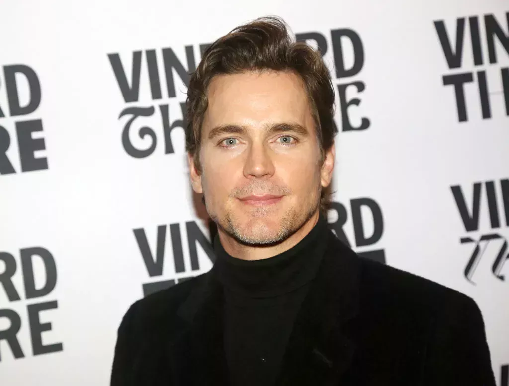 Matt Bomer in a black turtleneck and black jacket