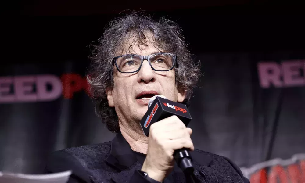 The Sandman creator Neil Gaiman speaks into a microphone at New York Comic Con 2022