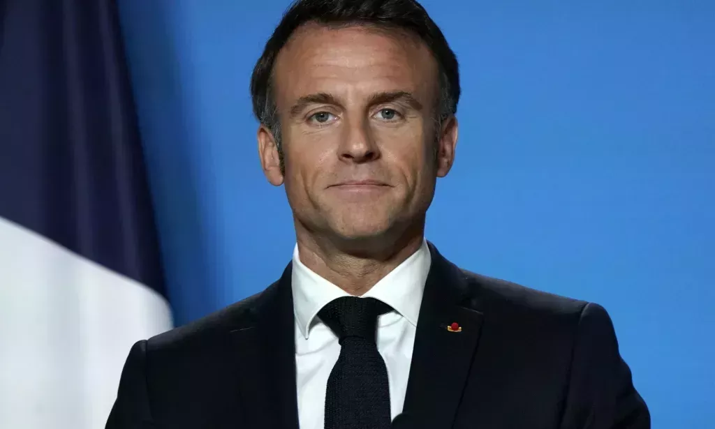 Emmanuel Macron looking directly forward on a blue set.