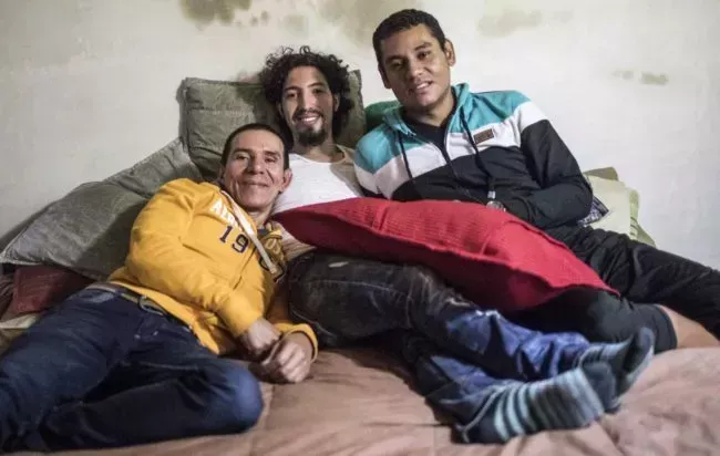 Alejandro Rodriguez (L), Victor Prada (C) and Manuel Bermudez pose for a photo at their home in Medellin, Colombia on June 17, 2017. The three men have gained legal recognition as the first "polyamorous family" in the country, where same-sex marriages were legalized last year. / AFP PHOTO / JOAQUIN SARMIENTO (Photo credit should read JOAQUIN SARMIENTO/AFP/Getty Images)