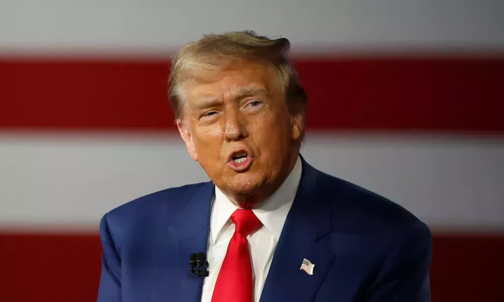 Republican presidential nominee, former U.S. President Donald Trump participates in a Town Hall debate. He's wearing a navy suit with a white shirt.