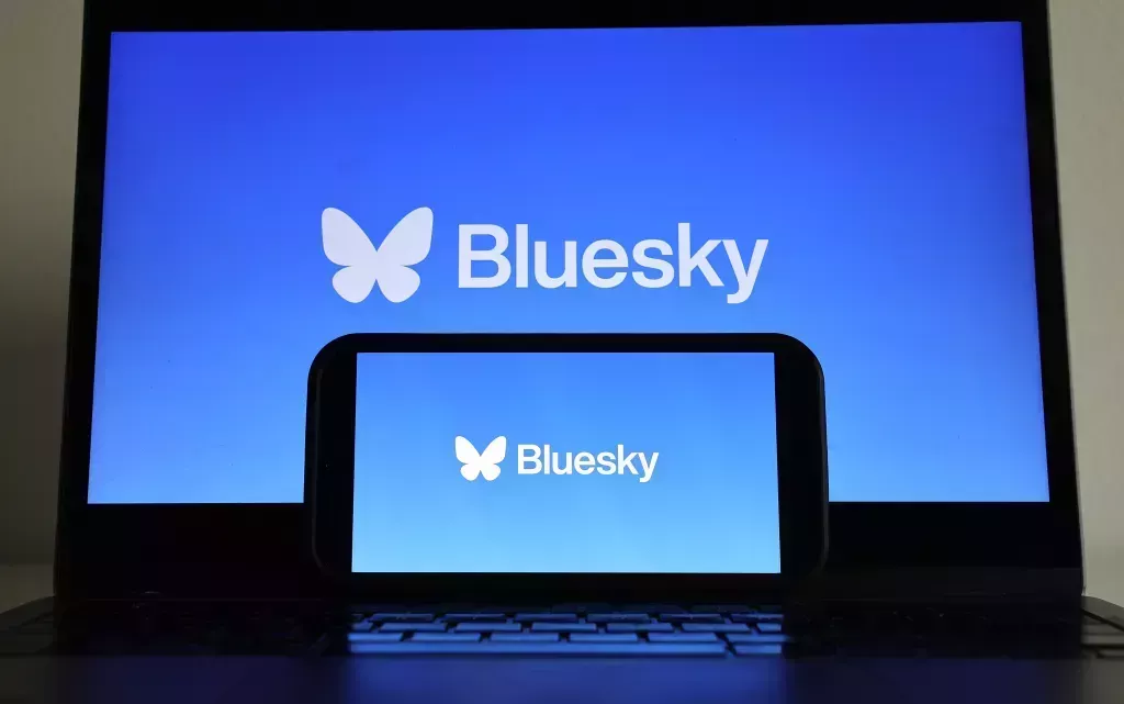 En esta foto ilustración, el logo de Bluesky se muestra en un teléfono celular y un monitor de computadora