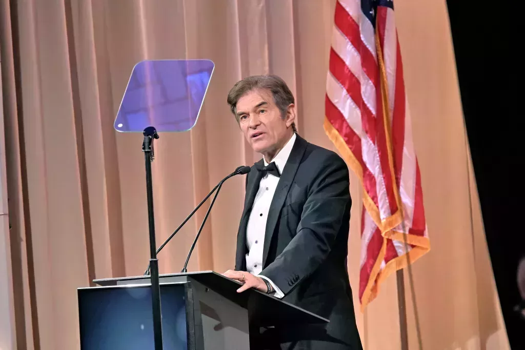 Mehmet Oz asiste a la ceremonia de Medallas de Honor de Ellis Island, él está de pie en un podio de orador con una bandera de EE. UU. detrás de él