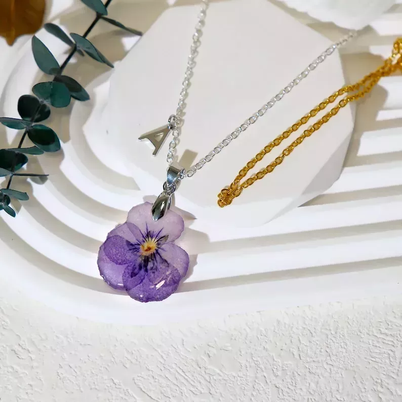 Un collar con una flor violeta seca sellada en resina